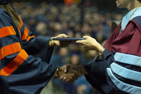 Graduate and President shake hands as diploma is received.