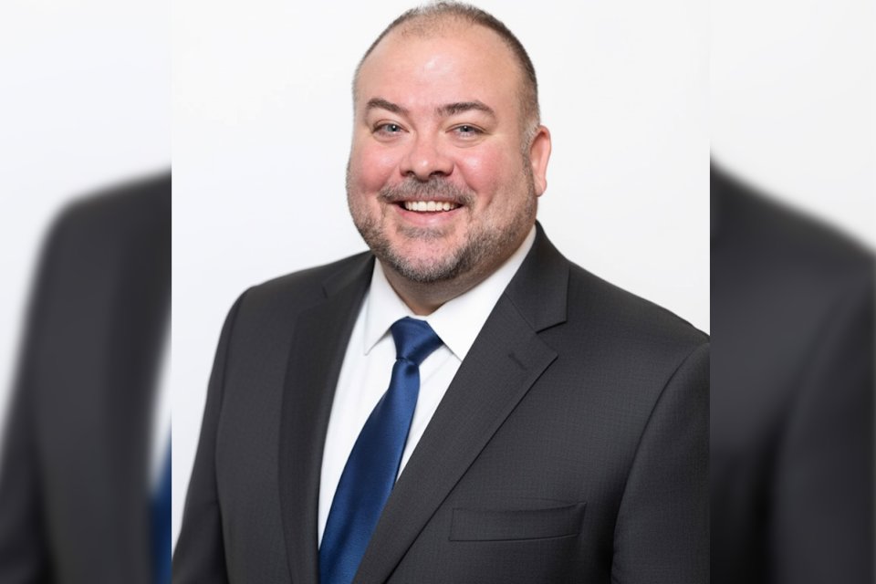Harol Coleman in dark suit, white shirt. and blue tie.